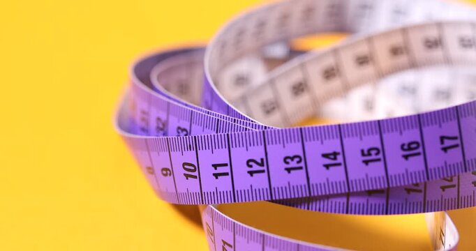 One measuring tape on orange background, closeup