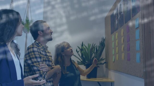 Woman reaching to place sticky note, team joining sorting corkboard under code overlay for business