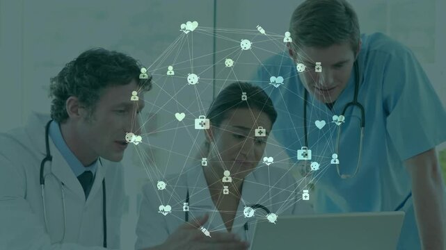 Medical team leaning over laptop, center doctor tapping laptop and activating icons, aligning care