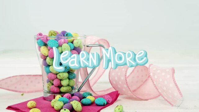 Camera crop shifting revealing cup spilling pastel candy while Learn More graphic drawing focus