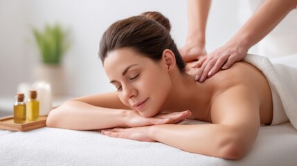Obraz premium Caucasian woman receiving a back massage in a serene spa setting, therapist applying oil on her upper back, soft lighting and natural elements visible in the background