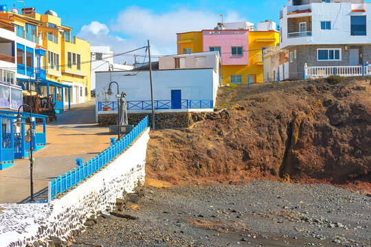 Seaside village of El Cotillo in Fuerteventura, Canary Islands, Spain. Colorful buildings overlook a rugged, rocky beach with its signature blue railings and a serene coastal atmosphere
