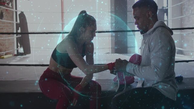 Coach wrapping boxer hands with wraps as boxer leaning in for training, hologram overlaying pair