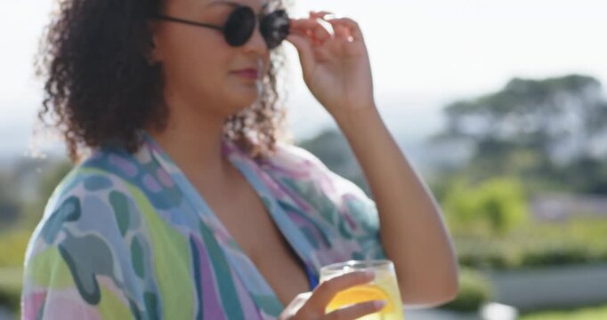 Adult woman in kimono holding lemon drink straw patio camera panning putting shades for sun sipping