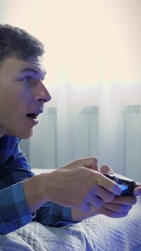 Man holding wireless controller, pressing buttons, playing game. Vertical video