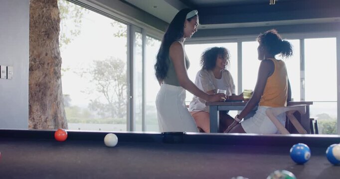 Female friends socializing, standing woman stepping closer at tall table, others raising glasses
