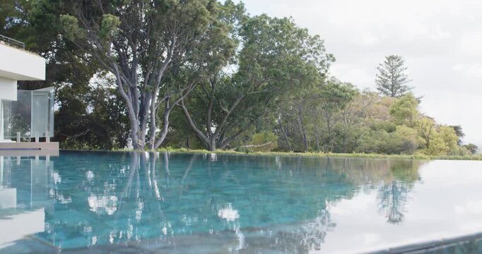 Slow camera movement is bringing infinity pool closer at home, revealing tree reflections and house
