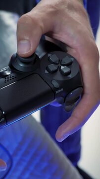 Hands holding joystick, pressing buttons, playing video game. Vertical video