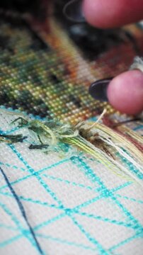 Woman embroidering beautiful nature on canvas, close up of hands. Vertical video