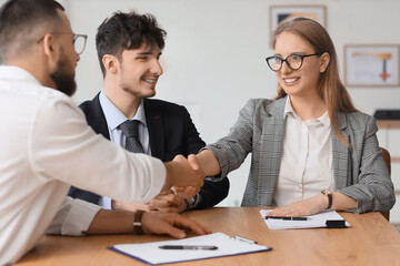 Fototapeta premium Male business mediator shaking hands with clients at table in office