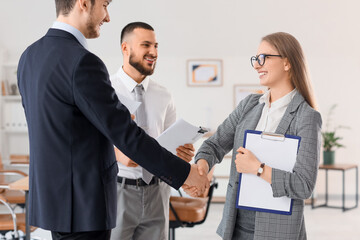 Male business mediator and clients shaking hands in office