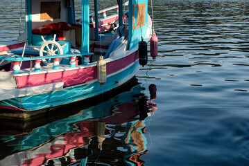 Obraz premium Pink and blue boat and its reflection on the sea
