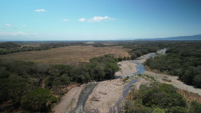Aerial over Guacimal River Costa Rica nears town of Judas De Chomas on sunny day Puntarenas Province