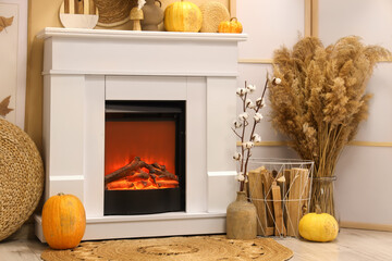 Naklejka premium Interior of modern living room with fireplace, folding screen and pumpkins