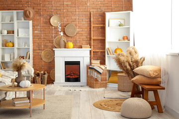 Naklejka premium Interior of living room with bench, coffee table, shelving units and autumn home decor on fireplace near brick wall