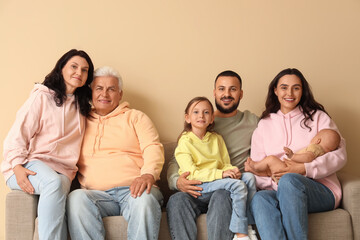Fototapeta premium Portrait of big family sitting on sofa against beige background