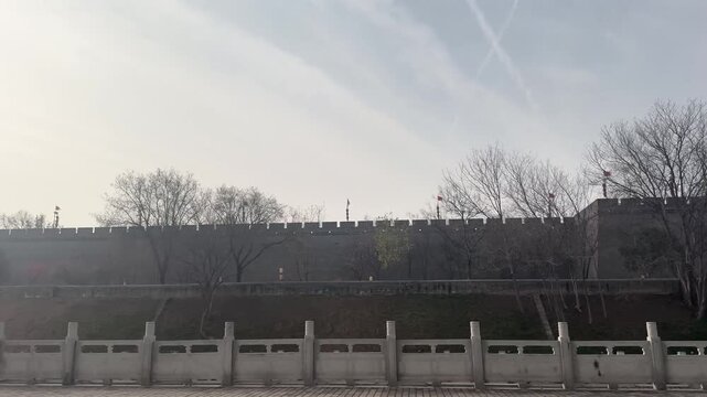 Old battlement of an ancient castle city wall in China, showing weathered stone crenellations with a blurred pathway and cloudy sky in the background, highlighting historical architecture and defensiv