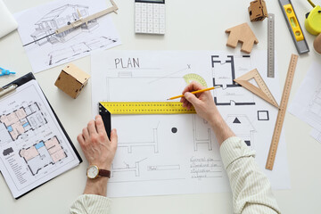 Male hands with ruler drawing zoning plan on table, top view