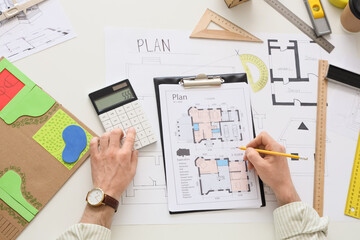Male hands with calculator working on zoning plan at table, top view