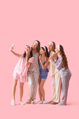 Obraz premium Group of young women in pajamas taking selfie on pink background. Hen Party