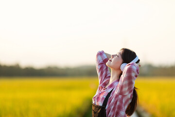 Fototapeta premium A beautiful Chinese woman listening to music in golden rice paddies in autumn