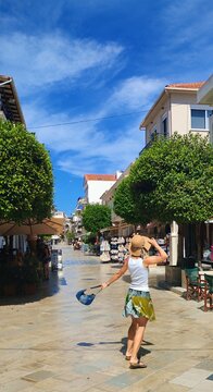 Zakintos,Greece-September 17,2025:Young woman in green skirt and straw hat with handbag danses at the emtpy street of old town 