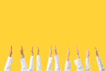 Hands of doctors on yellow background