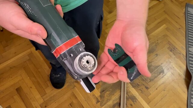 Closeup of hands holding electric oscillating multitool and broken plastic part, home repair and DIY maintenance, indoor workshop mood, practical fix for Fathers Day