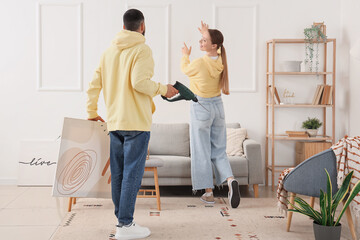 Young couple hanging painting at home