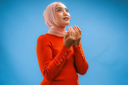 Religious beautiful Asian Muslim woman wearing a headscarf is praying to God.