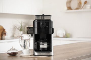 Naklejka premium Modern coffee machine and jug of water on table in kitchen, closeup