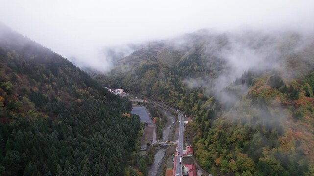 Drone view of village in valley with colorful autumn forest in rainy day. 4k real time footage b roll shot travel concept