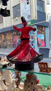 Vibrant red Whirling Dervish figurine performing Sema dance in an Istanbul souvenir shop. Traditional Turkish Sufi culture and Rumi spiritual symbol. Decorative Mevlana statue.