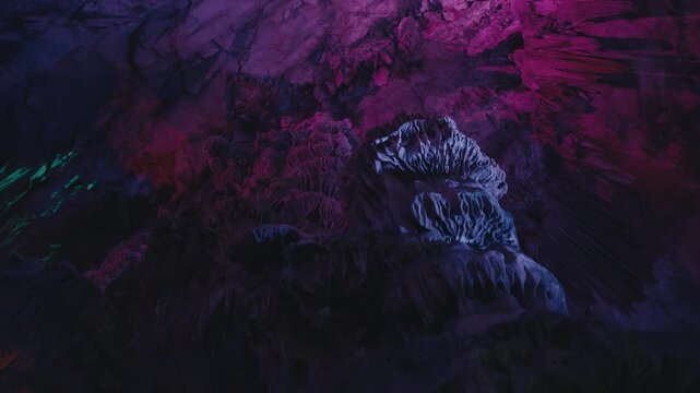 Abstract limestone formations inside St. Michael&rsquo;s Cave illuminated in deep blue, purple and magenta light, creating a dramatic underground atmosphere.