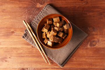 Fototapeta premium Bowl with pieces of fried tofu cheese on wooden background