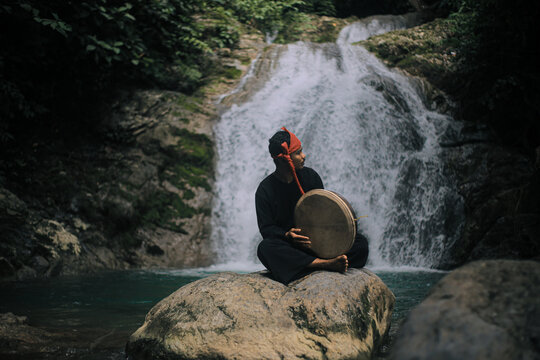 Acehnese Man Playing Traditional Rapai Drum at Waterfall &ndash; Cultural Music Performance in Tropical Nature, Indonesian Heritage and Travel Culture Concept