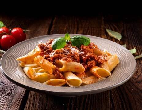 paccheri con ragu alla bolognese noodles with bolognese sauce on wooden table