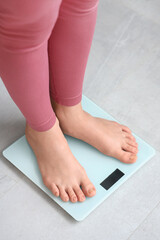Young woman standing on scales at home. Weight loss concept