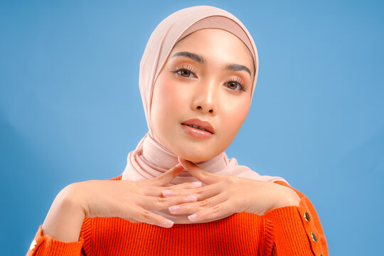 Beautiful young Asian Muslim woman wearing hijab with make up posing and looking to the camera.