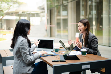 Fototapeta premium Businesswomen collaborating with laptop and tablet in a modern workspace, representing teamwork, communication, startup planning, leadership and corporate strategy.