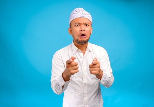 Disgusted young Balinese man wearing Indonesian traditional udeng posing with funny expression.