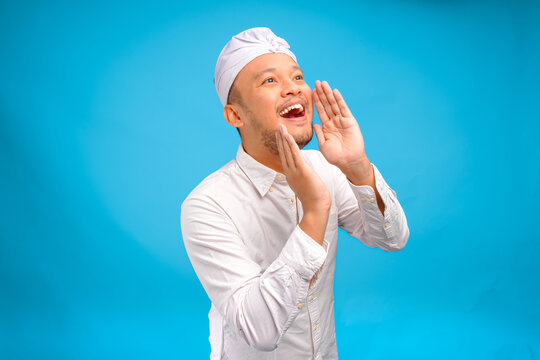 Excited young Balinese man wearing Indonesian traditional udeng shouting or screaming pose.