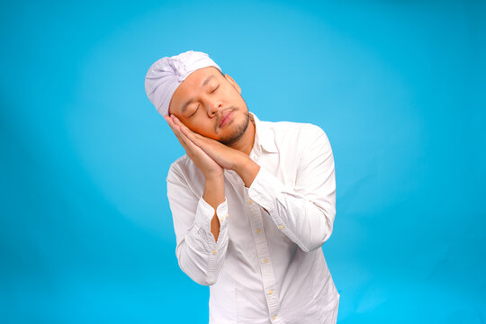 Tired young Balinese man wearing Indonesian traditional udeng falling asleep.