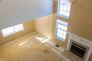 Naklejka premium Sunlight enters through windows in living room where floors are bare renovation work is ongoing.