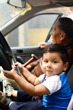 Latin toddler pretends to drive a car.