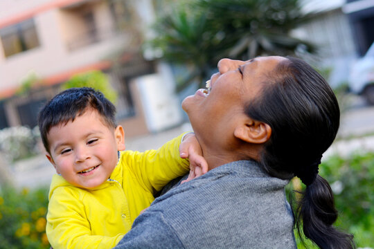 Happy latin mom and little son outside.