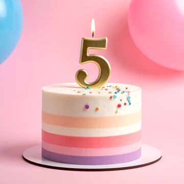 A small birthday cake with a lit candle in a gold number 5 on top