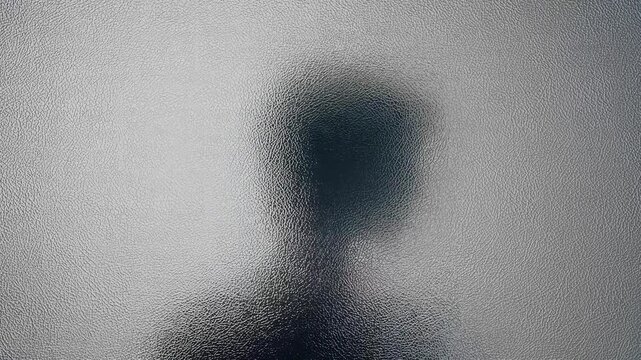 Silhouette of a person's head and shoulders seen through frosted glass