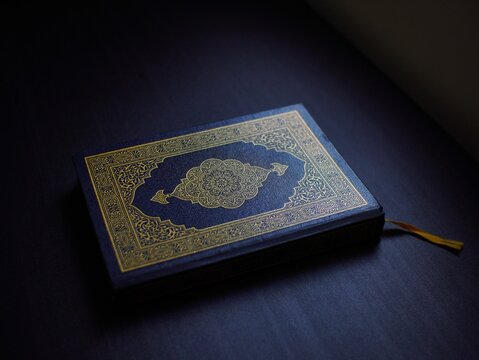 Holy Quran placed on a dark background with dramatic lighting, symbolizing Islamic faith, spirituality, religious study, and devotion in a peaceful atmosphere.