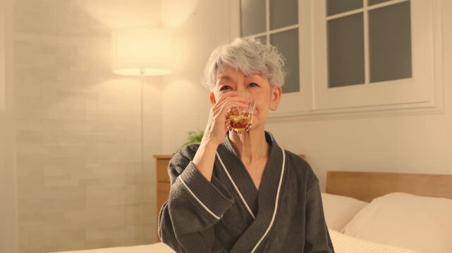 ガウンコート姿でロックグラスを持つシニア女性　ライフスタイルイメージ	